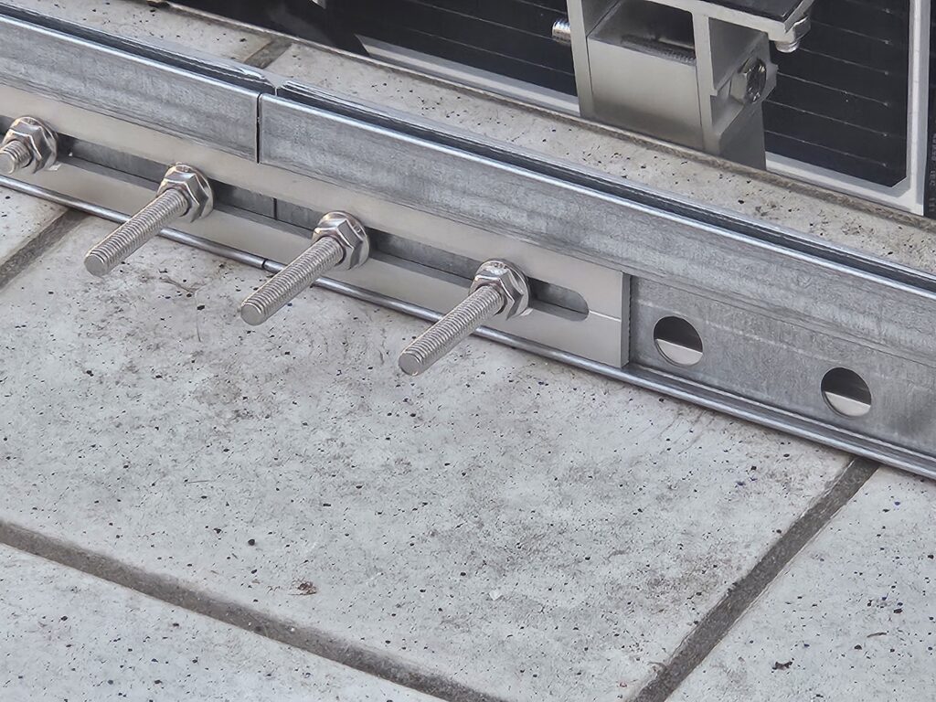Close-up of two mounting rails joined together with stainless steel bolts. The connection forms an extended support rail for a balcony solar system.
