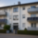 Weichgezeichnete Außenansicht eines Mehrfamilienhauses mit zwei gut erkennbaren Balkonkraftwerken an zwei Balkonen.